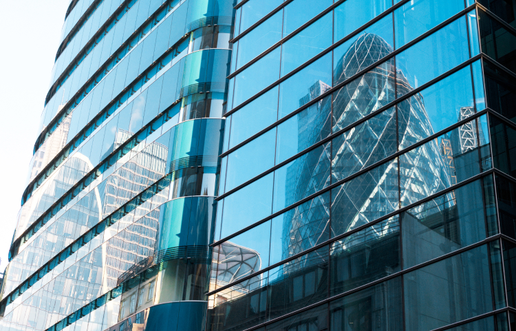 A reflection of a skyscraper is seen in the windows of another office building.